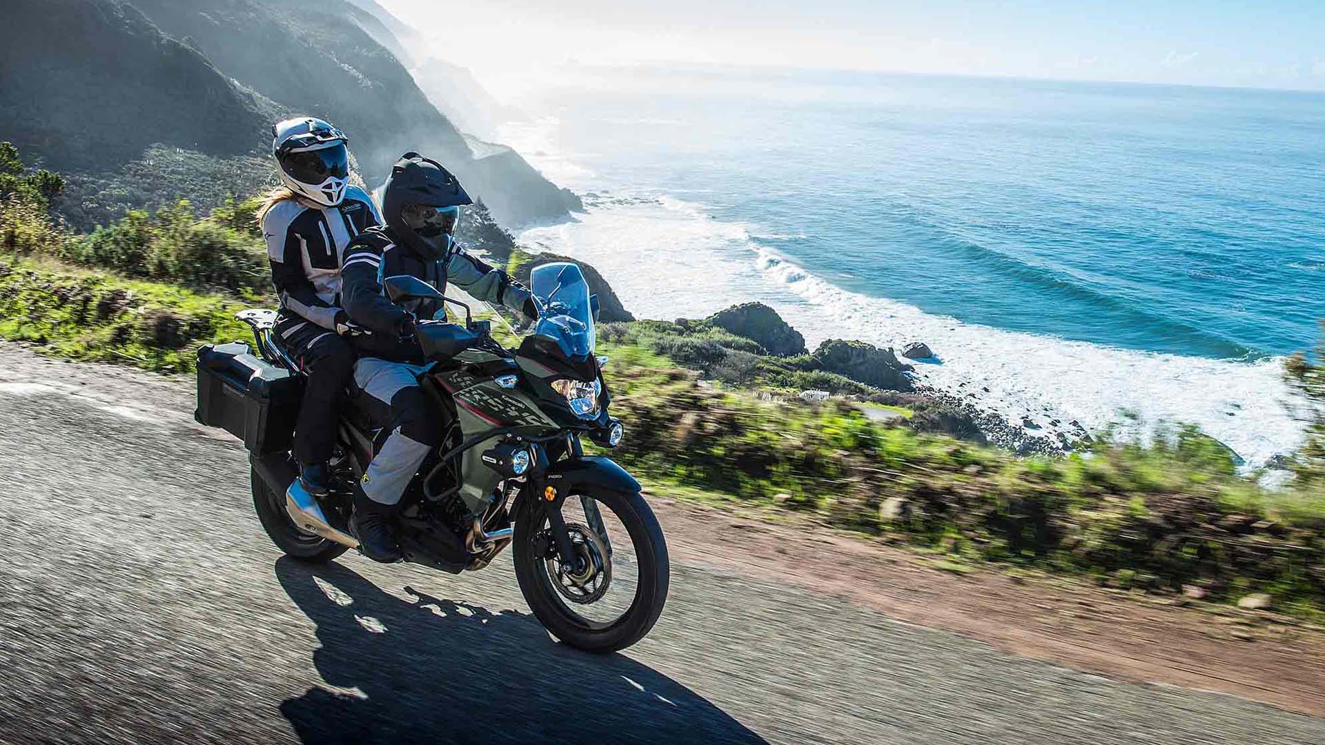 Two riders on the Kawasaki VERSYS-X 300 adventure motorcycle riding by the ocean.